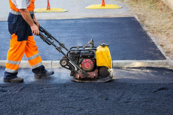 Worker Operating A Roller Compactor To Lay Asphalt Driveway